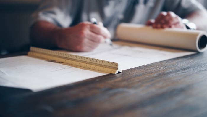 Working on construction drawings with a scale ruler at a desk